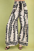 Wide-leg pants with black leaf pattern on a green background