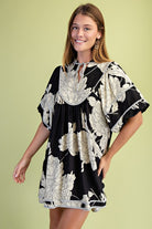 Woman wearing a black and white floral dress against a light green background