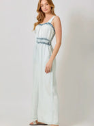 Woman wearing a denim romper  against a plain background