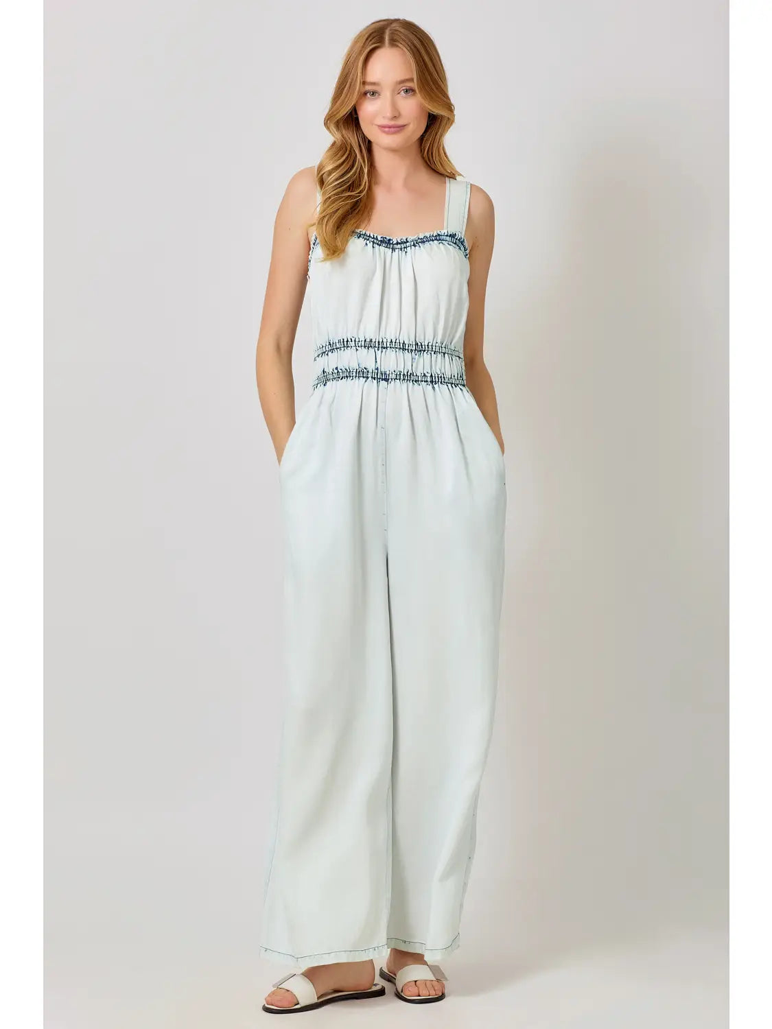 Woman wearing a light blue sleeveless jumpsuit with white background