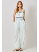 Woman wearing a light blue sleeveless jumpsuit with white background