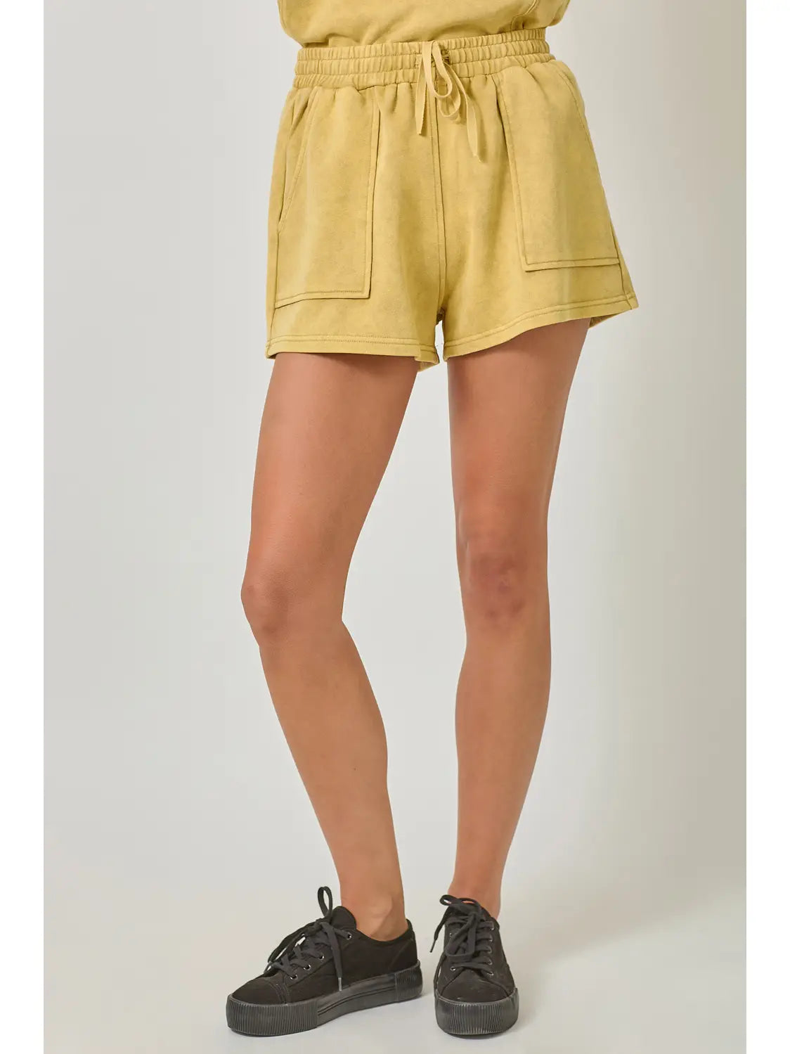 Yellow shorts worn by a person on a plain background