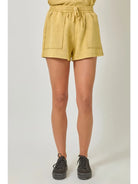 Person wearing mustard yellow shorts on a plain background