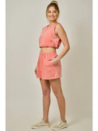 Woman wearing a coral outfit with a top and skirt on a plain background