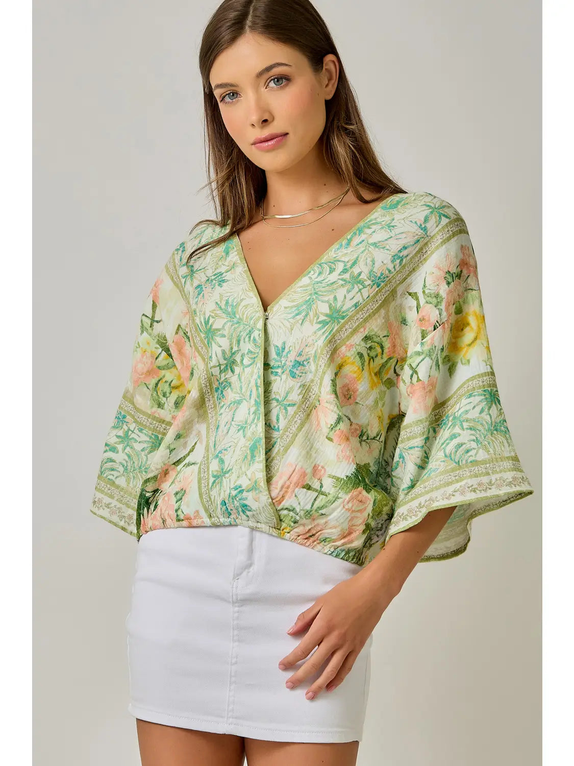 Woman wearing a floral kimono-style top with a plain background