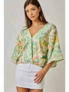 Woman wearing a floral kimono-style top with a plain background