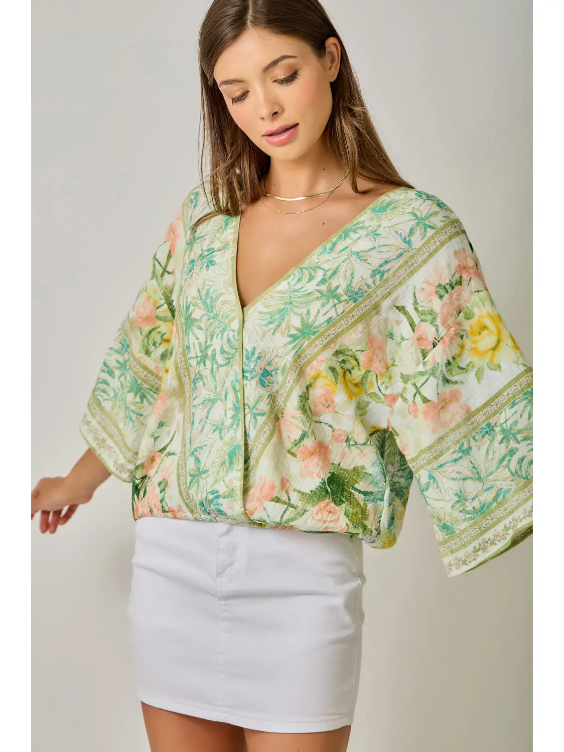 Woman wearing a floral kimono-style top with a plain background