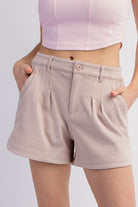 Person wearing beige shorts and a light pink top on a plain background