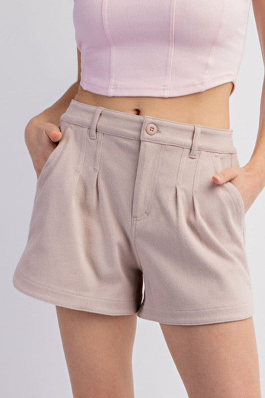 Person wearing beige shorts and a light pink top on a plain background