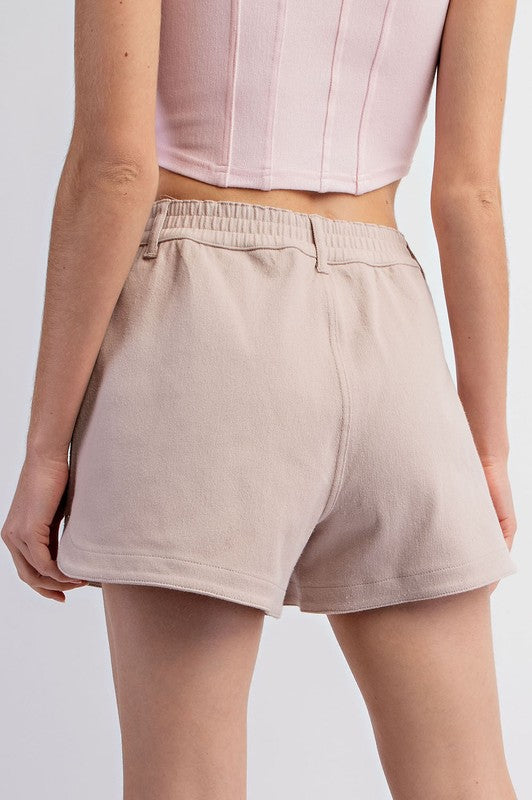 Beige shorts worn by a person on a white background