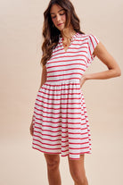 Woman wearing a red and white striped dress against a beige background