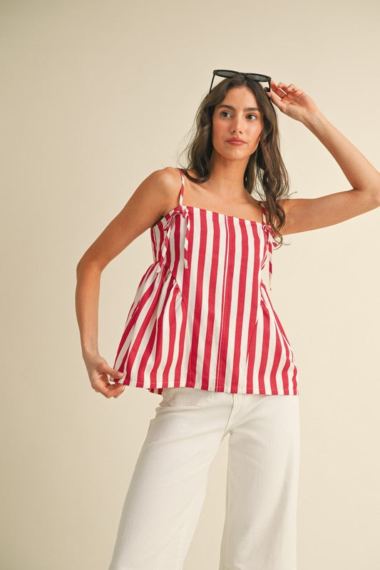 Woman wearing a red and white striped top and white pants against a beige background