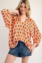 Model wearing orange blouse jean shorts on a white background