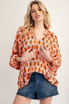 Model wearing orange ikat long sleeve blouse with jeans shorts