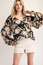 Model wearing black floral top with cream shorts