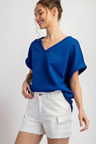 Model wearing textured blue top with White frayed shorts, white background