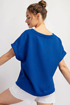 Back view of blue, textured shirt and white short shorts