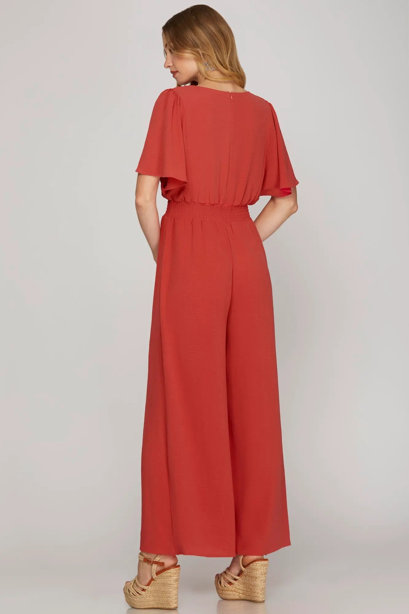 Back view of model wearing coral jumpsuit