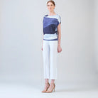 Side view of model, wearing purple and white top with white pants