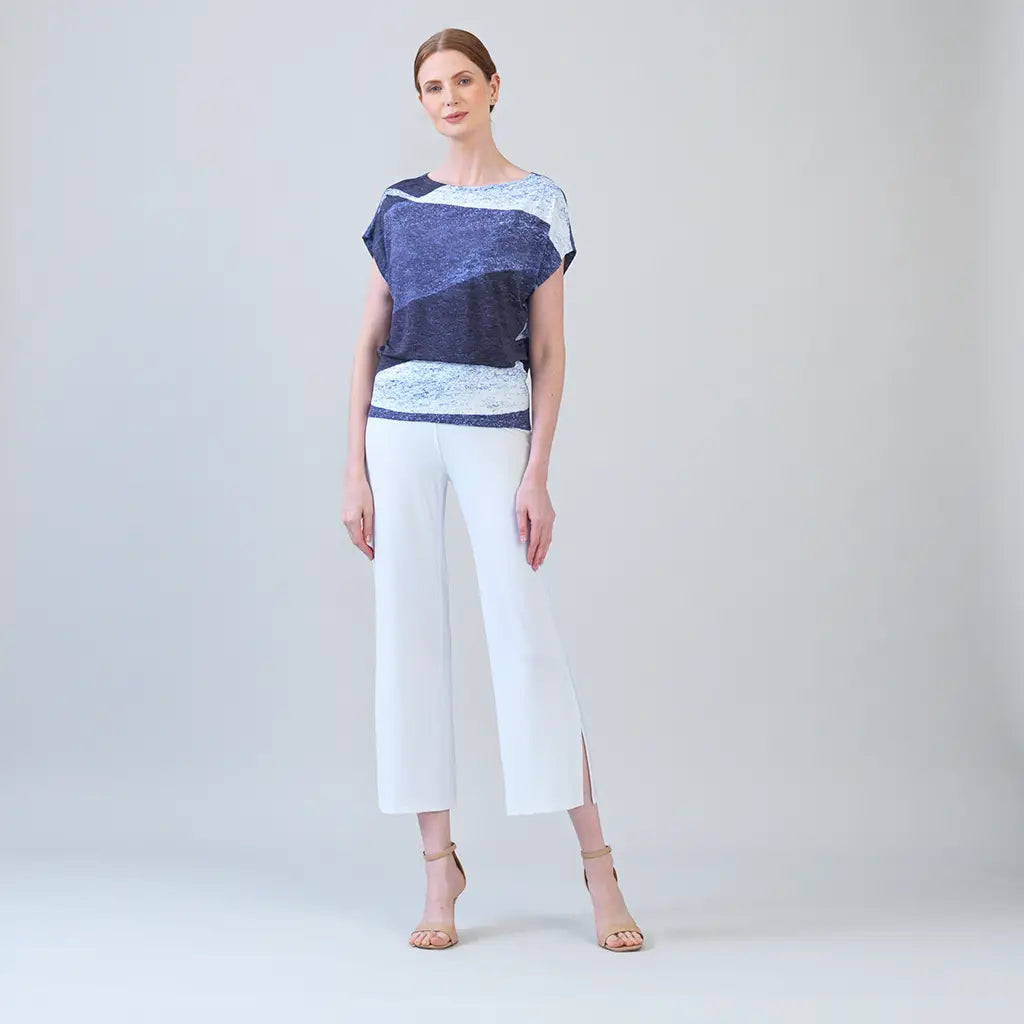 Model wearing purple and white top with white pants