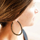 Model wearing black and gold earrings 