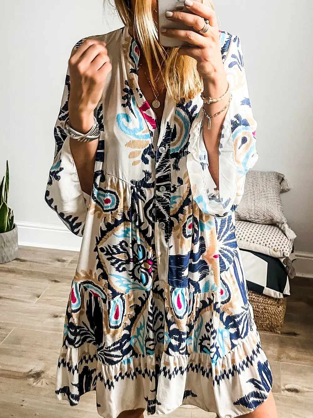 Woman wearing a colorful patterned dress taking a mirror selfie.