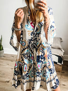 Woman wearing a colorful patterned dress taking a mirror selfie.