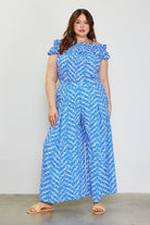 Model wearing blue printed pants and printed shirt to match against a white background