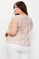 A woman shown from the back wearing a short-sleeve lace top with a beige and white floral pattern, paired with white pants, against a plain white background.