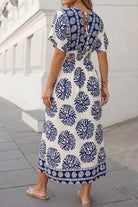 Woman wearing a blue and white patterned dress on a city street.