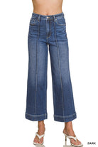 A model wearing a pair of dark blue wide-leg cropped jeans with front seam detailing, shown from the waist down on a white background.
