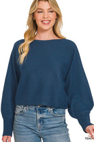 Woman wearing a teal sweater and blue jeans on a white background
