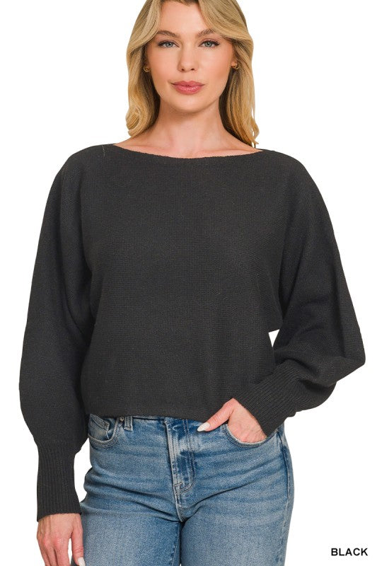 A woman wearing a black wide-neck long-sleeve sweater and blue jeans, shown from the waist up against a plain white background.