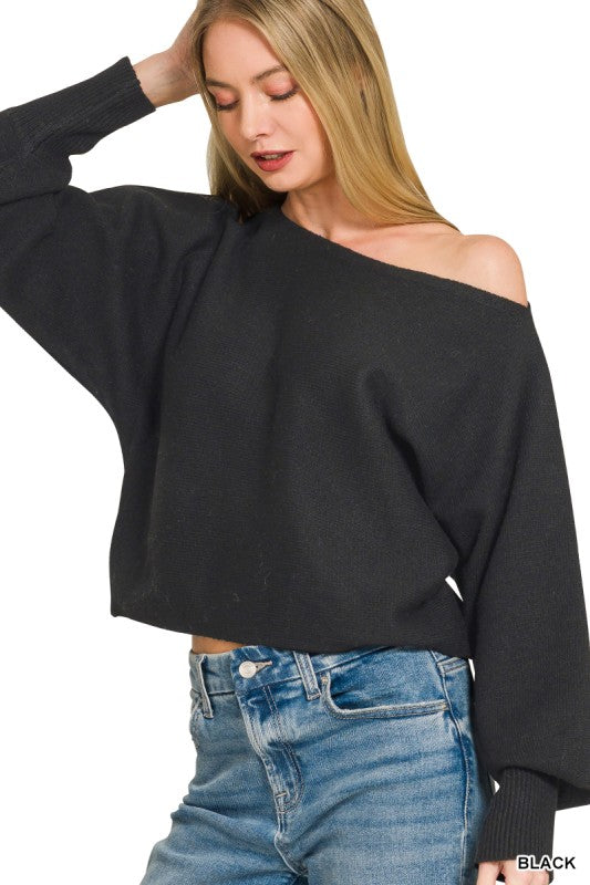 Woman wearing a black off-shoulder sweater and blue jeans on a white background
