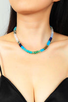 Necklace with multicolored beads worn by a person against a neutral background