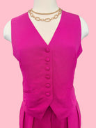 Mannequin wearing a bright pink dress with buttons on a pink background