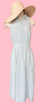 Light green dress with a beige sun hat on a pink background