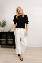 Woman in black top and white pants 