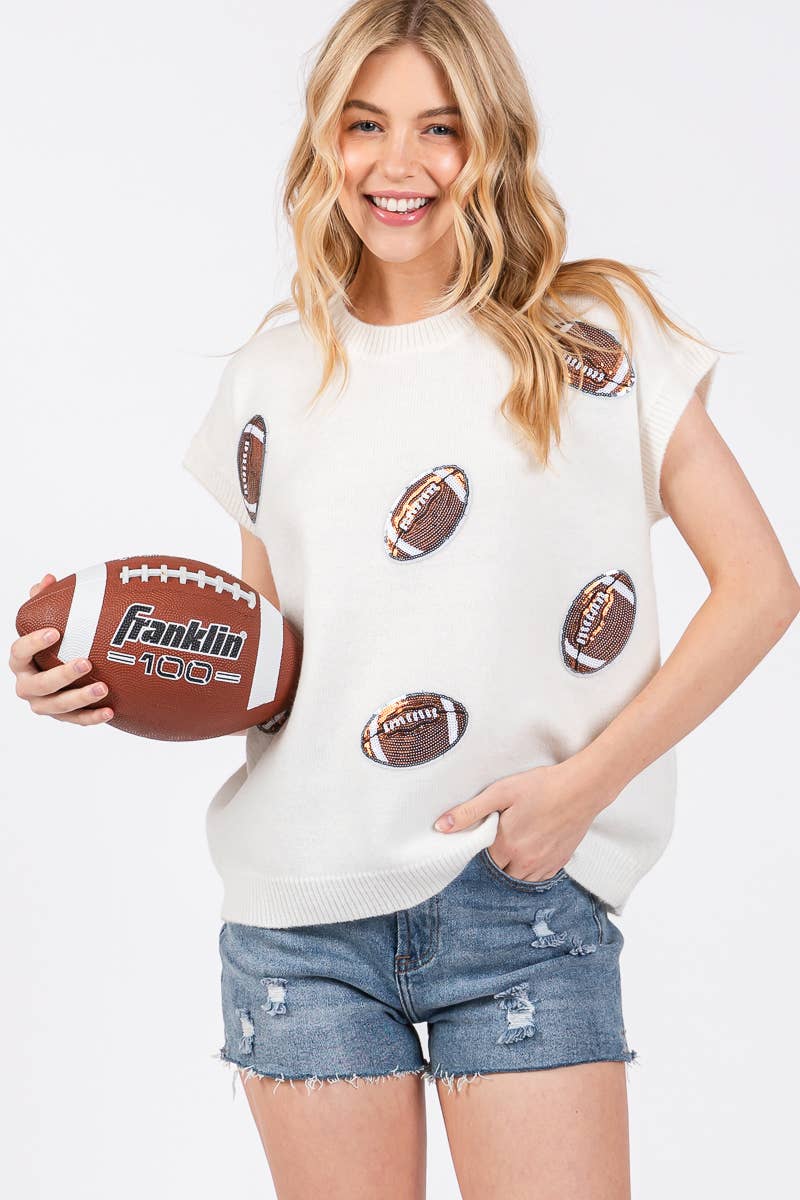 A woman modeling a white knit sweater with a football print, holding a brown football with 'Franklin 150' branding, against a plain white background.