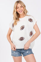 Woman wearing a white t-shirt with football graphics and denim shorts on a white background