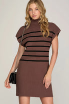 close up ofModel wearing chocolate mock neck dress with black stripes, a black purse and black heels 