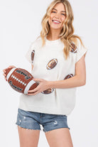 Woman holding a football wearing a white t-shirt with football graphics on a white background