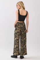 Woman wearing camouflage pants and a black top on a white background