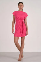 Woman wearing a bright pink dress with a tie waist 